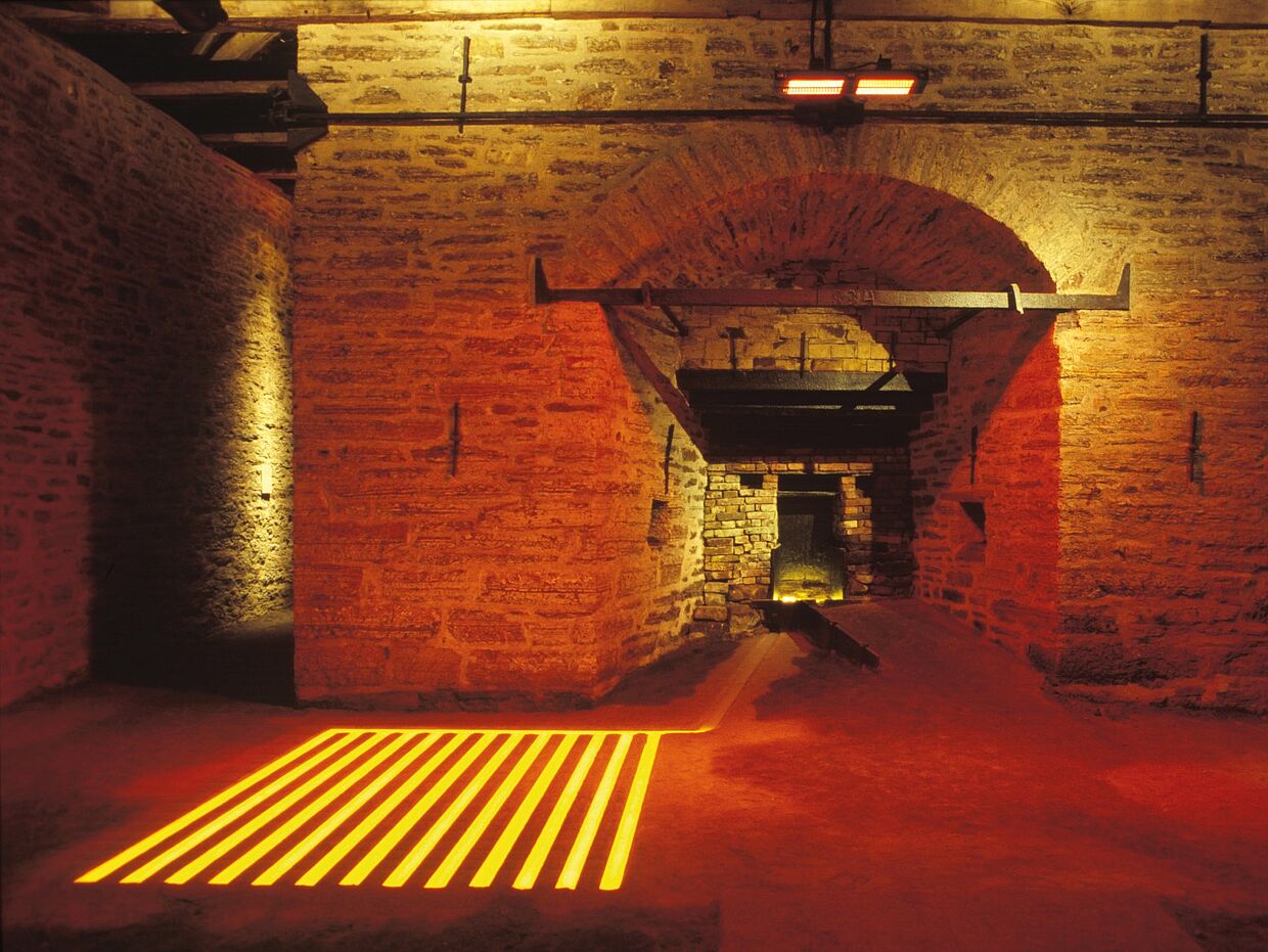 Der Hochofen der Luisenhütte, beleuchtet von orangefarbenem Licht, das an Hitze und Glut erinnert. 